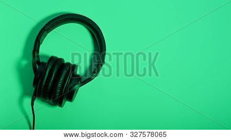 Black Over Ear Headphones Closeup On Blue Background, Top View. Minimal Music Background, Copy Space
