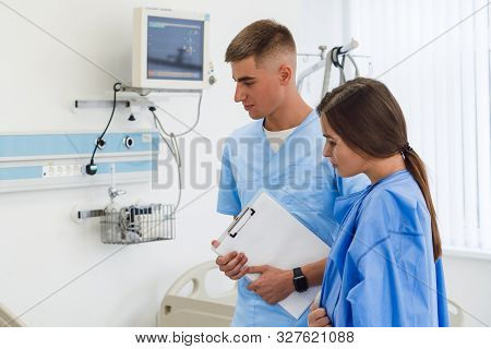 Doctor Physician Consulting With Female Patient In Hospital Exam Room. Checking Medical Results. Med