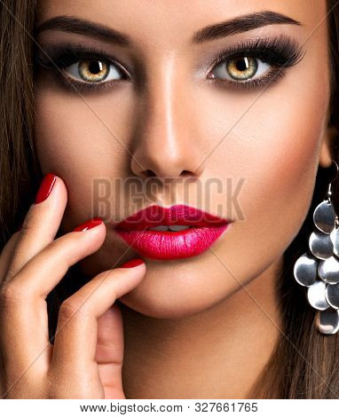 Closeup portrait of beautiful seductive woman with dark brown eye makeup and bright red lips and nails