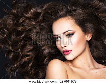 Beautiful woman with long bown hair. Portrait of an sensual adult girl with curly hair.