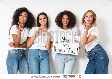 Photo of a happy young women multiracial friends posing isolated over white wall background holding blank with compliments text.