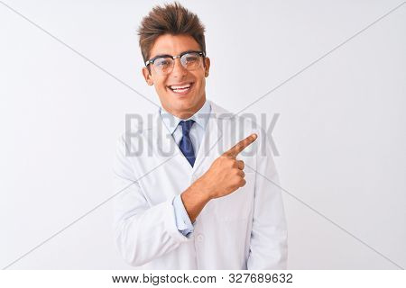 Young handsome sciencist man wearing glasses and coat over isolated white background cheerful with a smile on face pointing with hand and finger up to the side with happy and natural expression