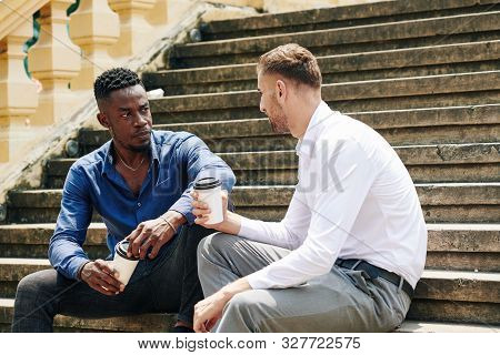 Serious Young Black Businessman Drinking Take Out Coffee And Listening To Colleague When Thay Are Re