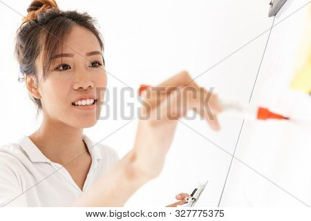 Attractive confident asian businesswoman presenting new project at the blankboard isolated over white background