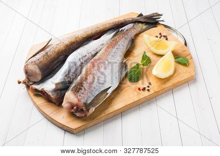 Raw Fresh Pollock Fish On A Wooden Board With Lemon