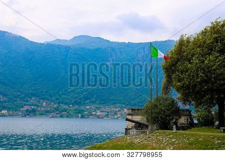 Italian Flag And Gun With Alps In Background, Lake Como In Mandello Del Lario.