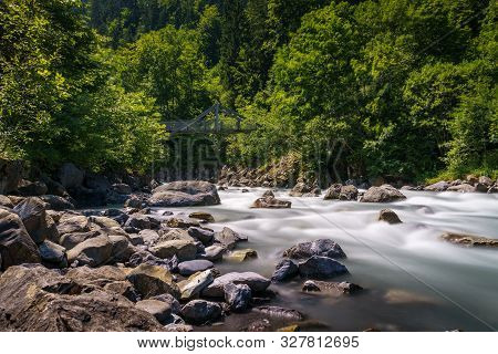 Kander River Flowing Near Blausee Lake In The Bernese Oberland, Switzerland, With A Footbridge And S