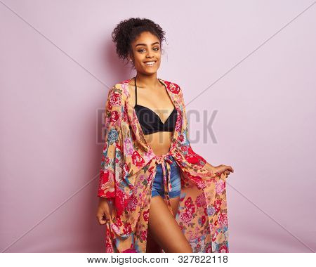 Young beautiful african american woman on vacation standing wearing bikini and colorful caftan
