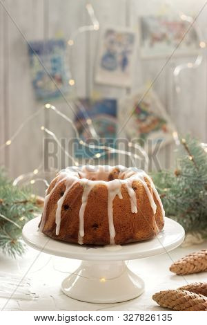 Pie With Raisins And Icing From Powdered Sugar On The Background Of Fir Branches And Garlands. Rusti