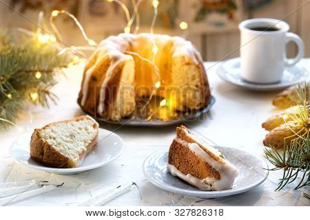 Pie With Raisins And Icing From Powdered Sugar On The Background Of Fir Branches And Garlands. Rusti