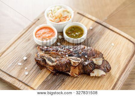 Beef Meat Cut According To The Argentine Style, Called Asado. With Pickled Cabbage And Two Sauces. S