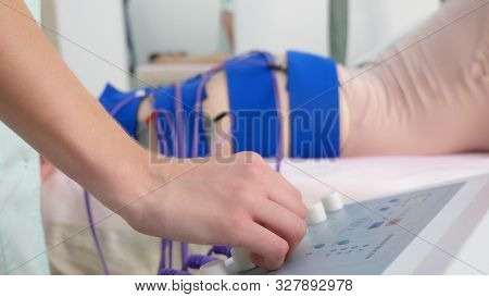 The Girl Lies On The Couch And Receives The Procedure Of Myostimulation On Her Legs And Buttocks In 
