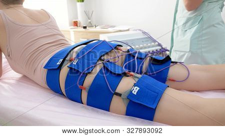 The Girl Lies On The Couch And Receives The Procedure Of Myostimulation On Her Legs And Buttocks In 