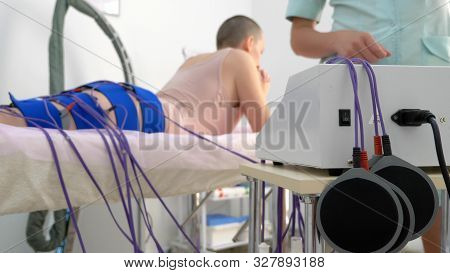 The Girl Lies On The Couch And Receives The Procedure Of Myostimulation On Her Legs And Buttocks In 