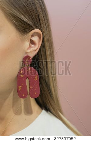 Plastic Handmade Earrings On The Ears Of The Blonde. Earrings Made Of Plastic With Redcolour.