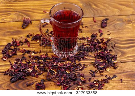 Glass Cup Of Red Hibiscus Tea (carcade, Roselle) On Wooden Table