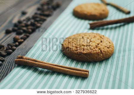 Close-up Three Tasty Oatmeal Cookies Laying At The Green Stripped Textile Kitchen Towel With Sticks 