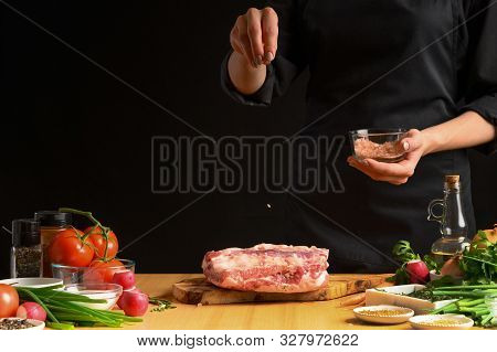 Chef Cooks Pork Ribs. Sprinkling With Salt On A Background With