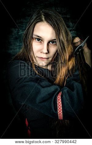Portrait Of Young Long Haired Woman Wearing A Medieval Costume. Standing Pose Pointing A Sword To Th