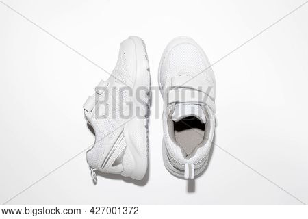 Top View White Kid Sneakers With Velcro Fasteners, One Sneaker On The Side Isolated On A White Backg