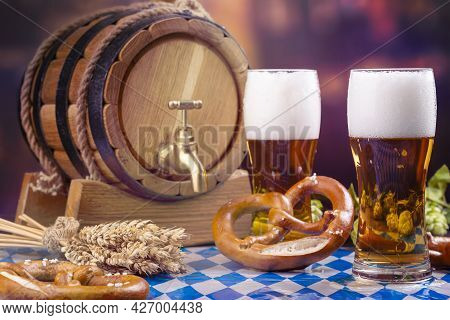 Oktoberfest Beer Barrel And Beer Glass, Pretzels, Wheat And Hops On Wooden Table