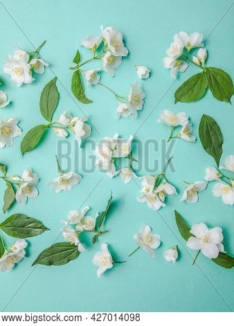 Pattern Of Bud Jasmine And Leaves Scattered On A Green Background, Overhead View. Flat Lay. Pattern 