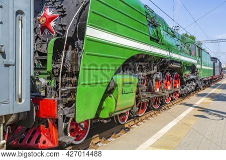 Green Retro Steam Locomotive At The Railway Station On A Sunny Day