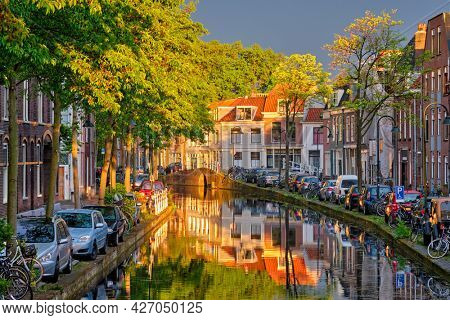 Delt canal with old houses and cars parked along on sunset. Delft, Netherlands