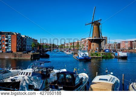 View of the harbour of Delfshaven with the old grain mill known as De Destilleerketel. Rotterdam, Netherlands