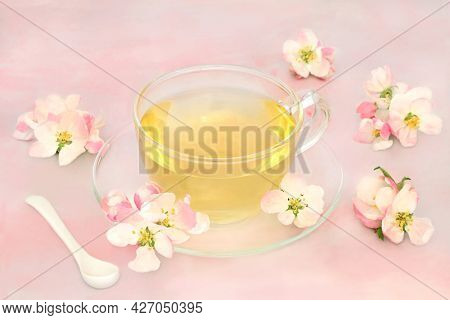 Herb tea hot drink with apple blossom very high in antioxidants and  beneficial for the digestive and nervous systems and skin conditions such as acne and pigmentation. On pink marble.