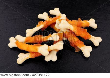 Crunchy Chicken And Calcium Bone Shaped Dog Treats On A Slate Stone Background