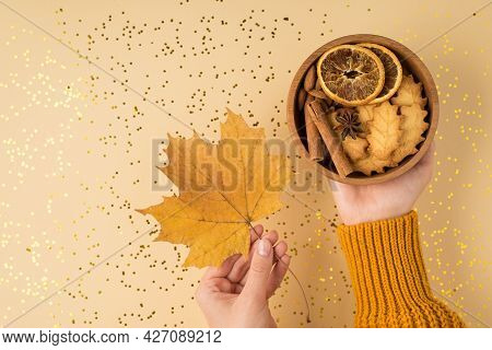 First Person Top View Photo Of Woman's Hands In Yellow Pullover Holding Yellow Maple Leaf And Wooden
