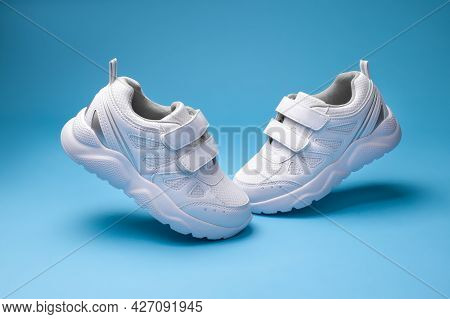Side View White Kid Sneakers With Velcro Fasteners Fly In The Air In Form Of The Letter V Isolated O