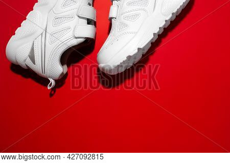 Top View Macro Part Of Two White Unisex Sneakers In The Corner With Copy Space Isolated On A Red Bac