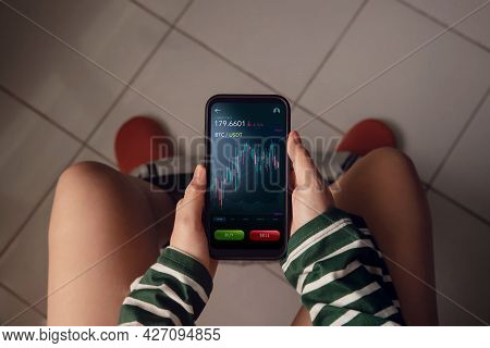 Cryptocurrency Investment Concept. Person Using Mobile Phone In Toilet At Home To Buy And Sell Bitco