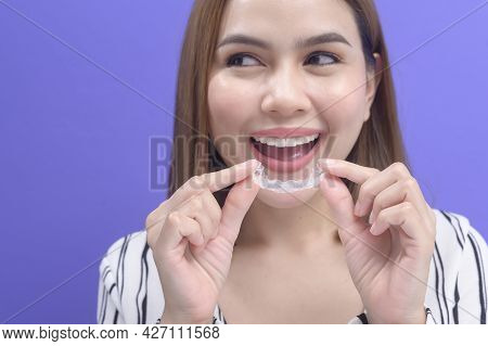 Young Smiling Woman Holding Invisalign Braces In Studio, Dental Healthcare And Orthodontic Concept..