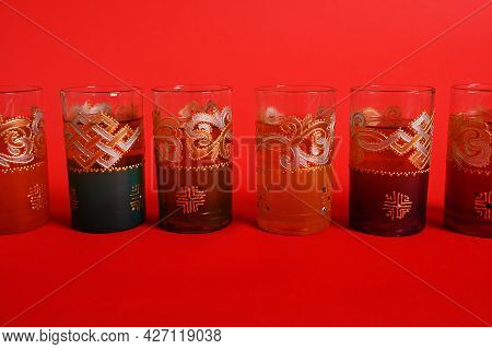 Multicolored Glasses For Moroccan Green Mint Tea, Decorated In Oriental Style. Isolated On Red Backg