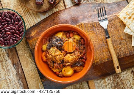 Jewish Dish Chelnt With Meat On The Table In A Plate On A Stand Next To The Ingredients And Matzo. H
