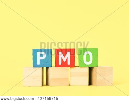 Colorful Wooden Cubes With Text Pmo Against Yellow Background.