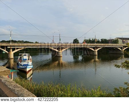 Beautiful Summer Landscape With Passenger Boat Docking On The River, Concrete Pedestrian Bridge