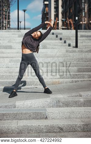 Pleased Athletic Female Doing A Lateral Flexion Outdoors