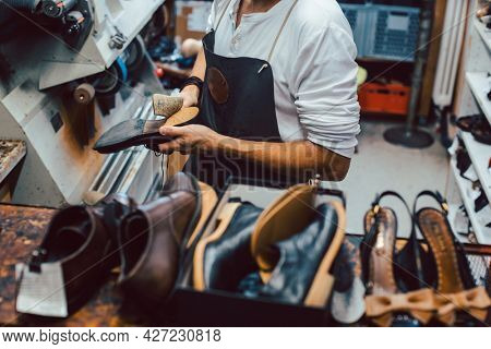 Shoemaker with shoes to repair on a rack in his workshop