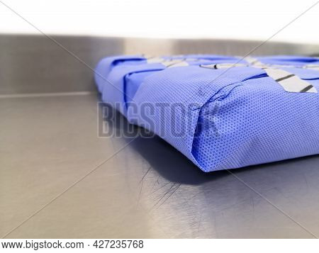 Side View Of Surgical Instruments Set Wrapped With Disposable Blue Drape Sheet. Selective Focus