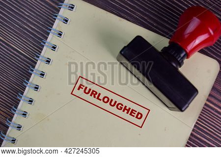 Red Handle Rubber Stamper And Furloughed Text Isolated On Wooden Table.