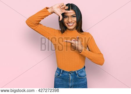 Young latin transsexual transgender woman wearing casual clothes smiling making frame with hands and fingers with happy face. creativity and photography concept. 