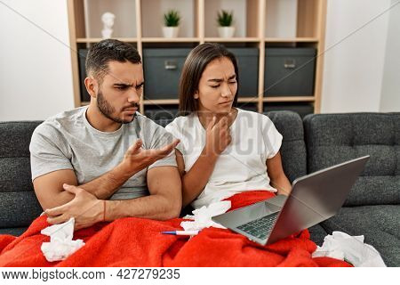 Young latin ill couple having medical teleconsultation using laptop at home.