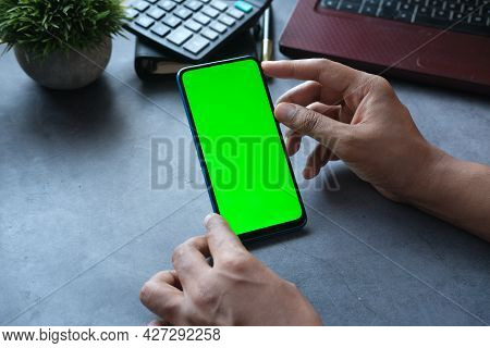 Rear View Of Man Hand Using Smart Phone On Office Desk