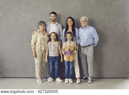 Studio Portrait Of Happy Multi Generational Family Standing Together And Smiling