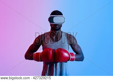 Strong Black Sportsman In Vr Headset Putting Boxing Gloves Together In Neon Light