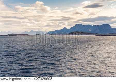 Stormclouds With Sun Shining Through Them Above Dramatic Mountain Range Of Lofoten Islands, Viewed F